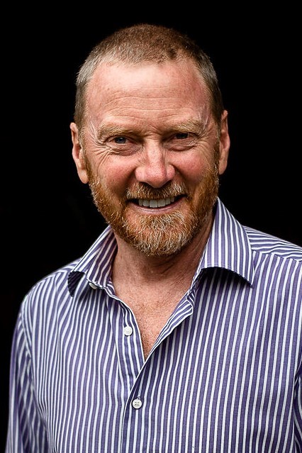 a close up of Facilitator Steve Willing who smiles at the camera wearing a striped blue and white shirt.